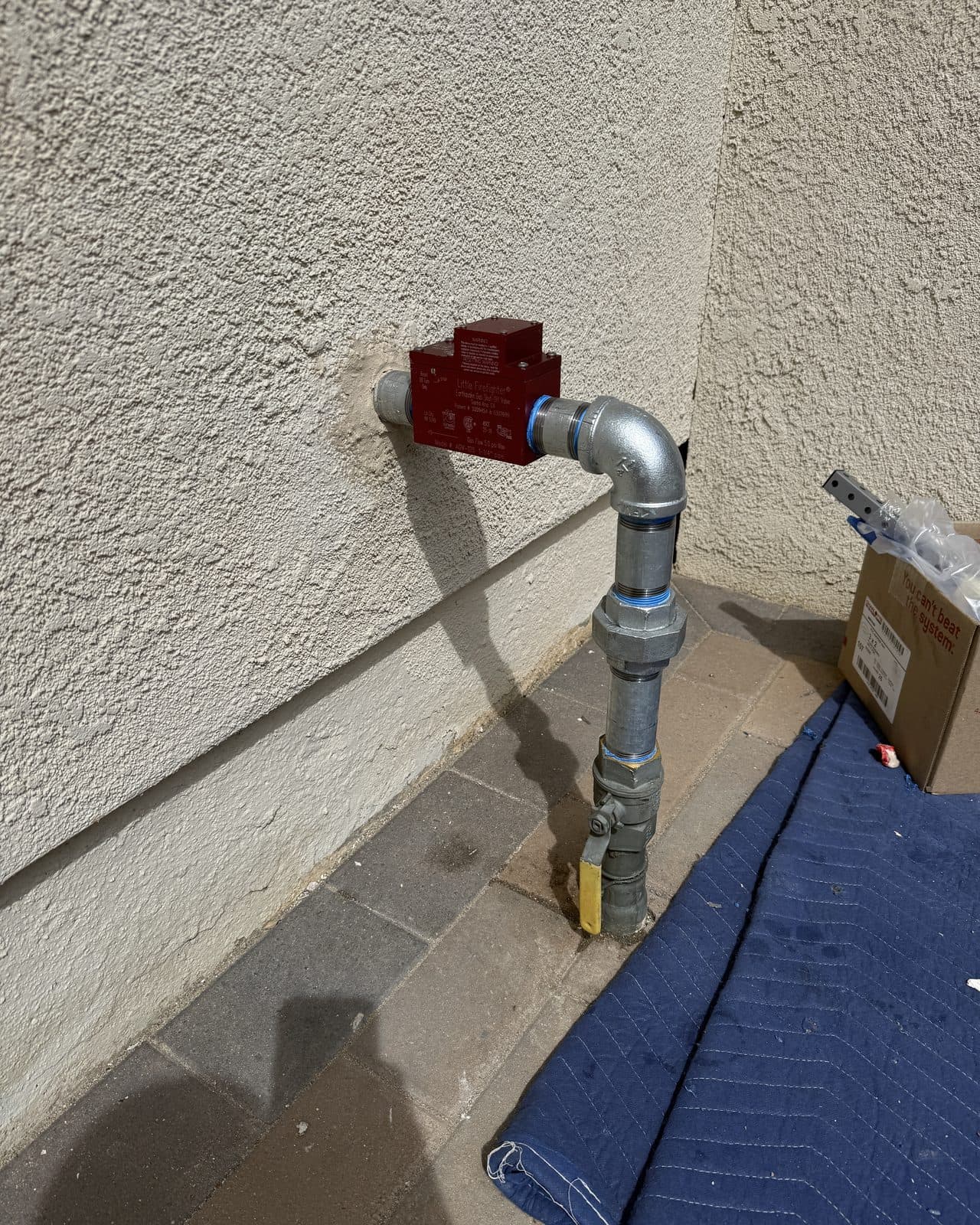 Gas shutoff valve and galvanized riser at an exterior stucco wall