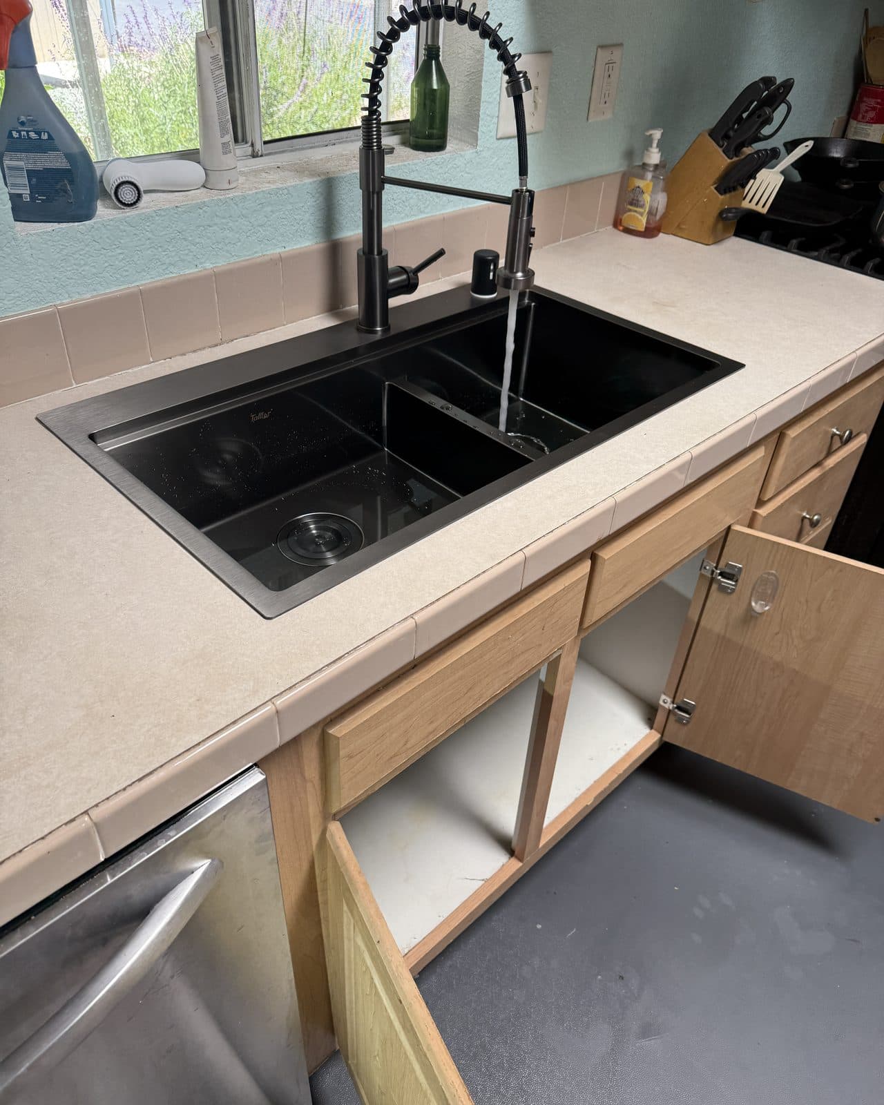 Black kitchen sink with a pull down faucet running water