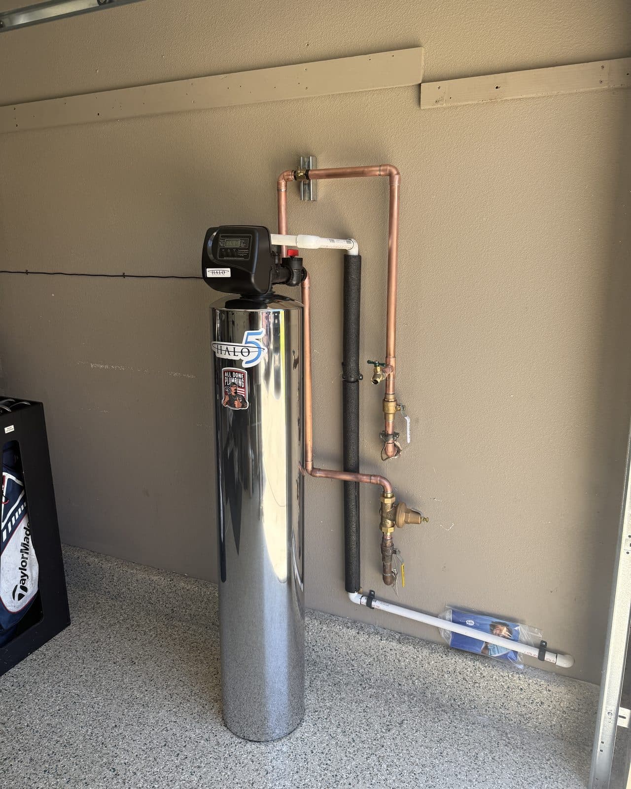 Stainless water softener cylinder connected to copper supply lines