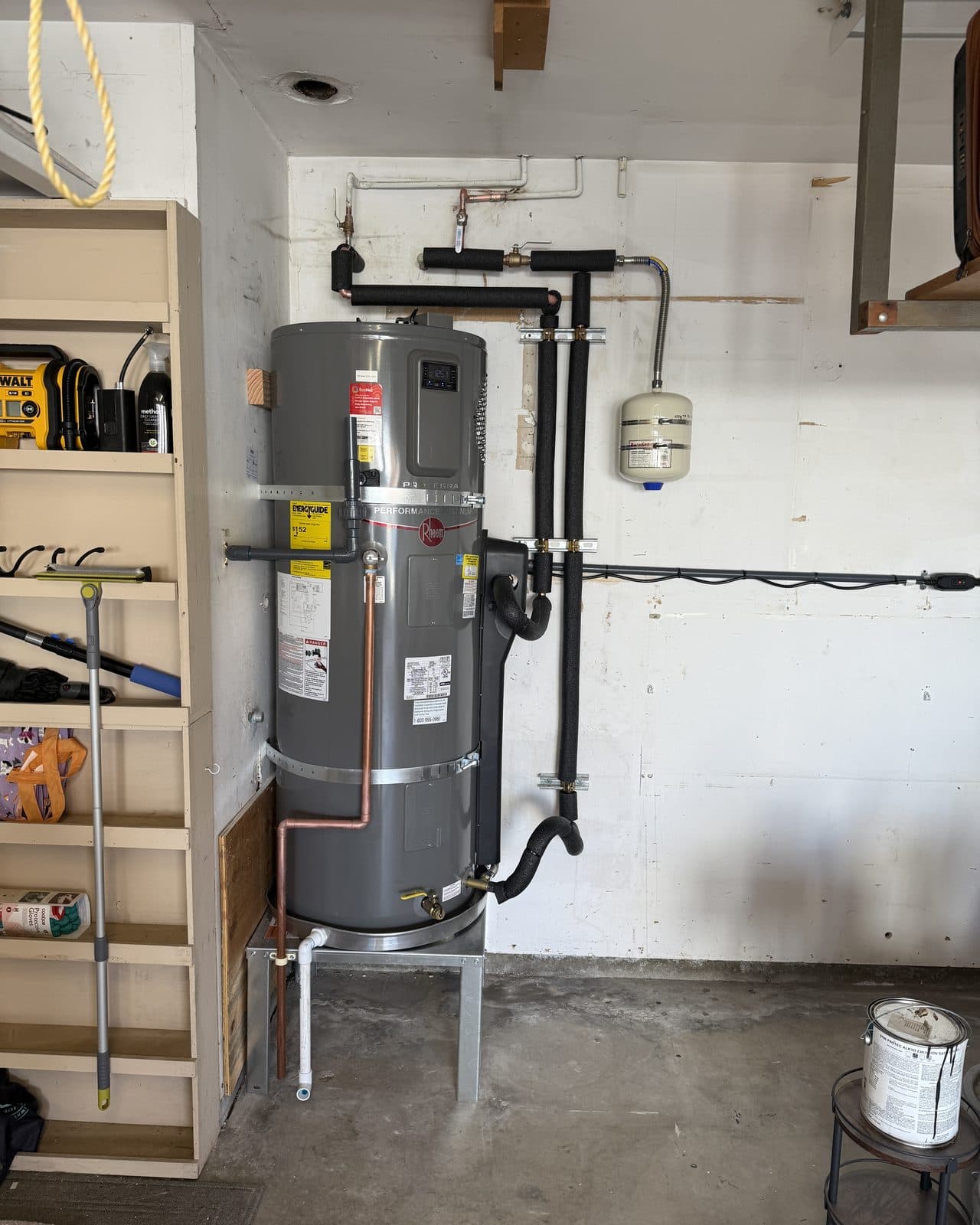 Tank water heater on a metal stand with an expansion tank above it