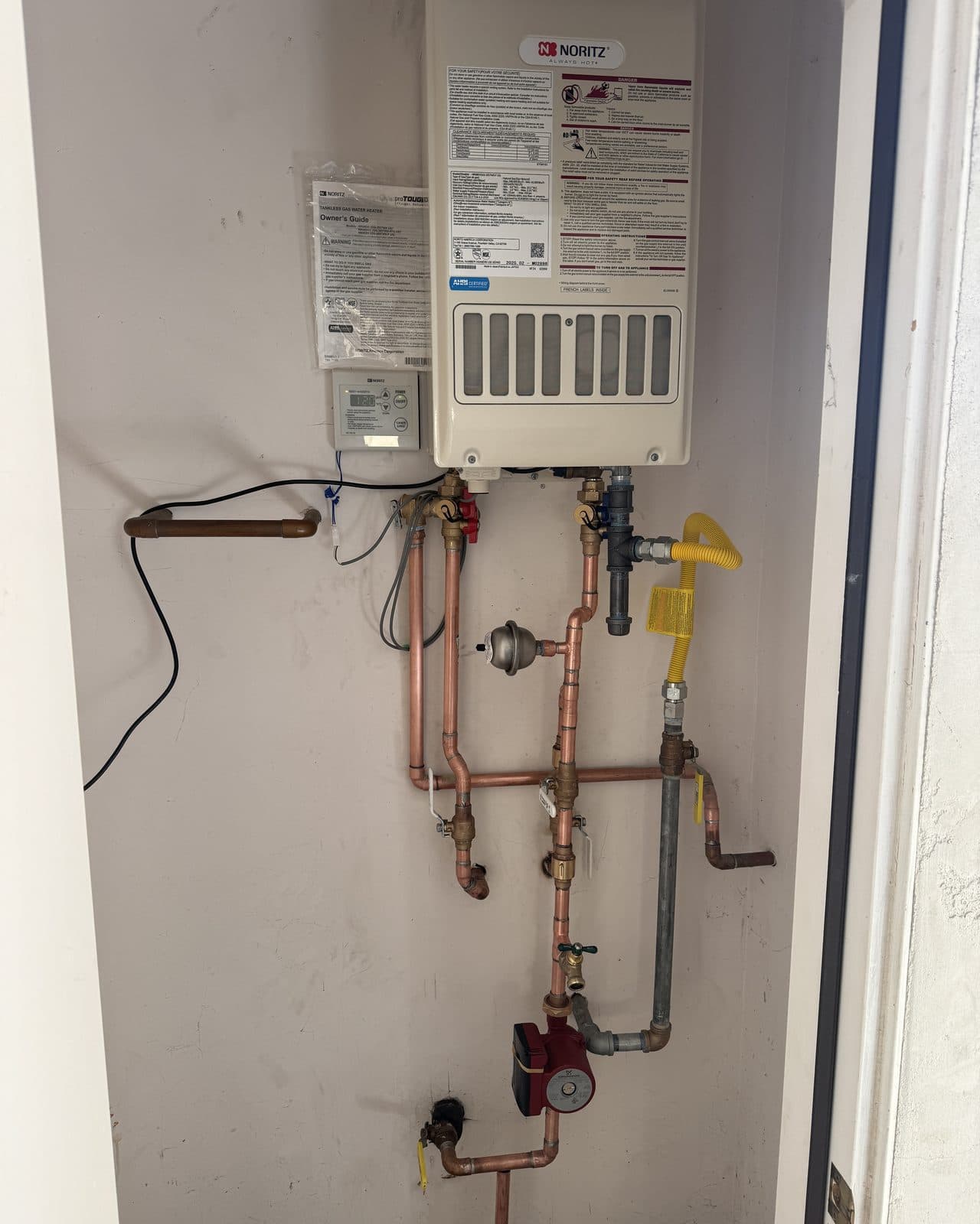 Tankless water heater above a copper manifold with a recirculation pump