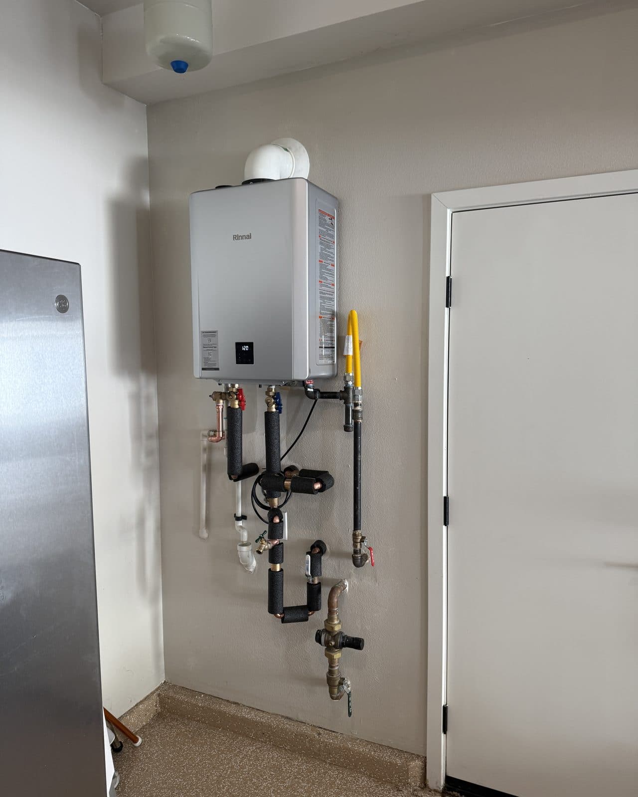 Wall mounted tankless water heater with gas and water connections below it